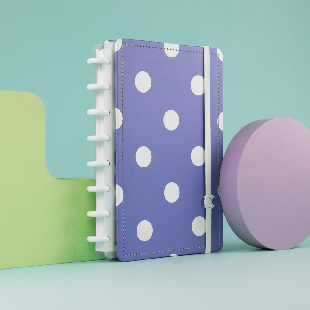 Caderno inteligente de capa lilás com bolinhas brancas.